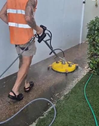 High-pressure cleaning of a concrete driveway and path, showing the clean strip against the dirty section